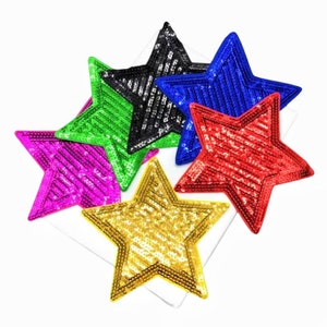 May include: A collection of sequined star-shaped patches in various colors, including gold, red, blue, black, green, and pink. The stars are arranged on a white surface, showcasing their shimmering texture and vibrant hues. These patches are ideal for adding a decorative touch to clothing or accessories.
