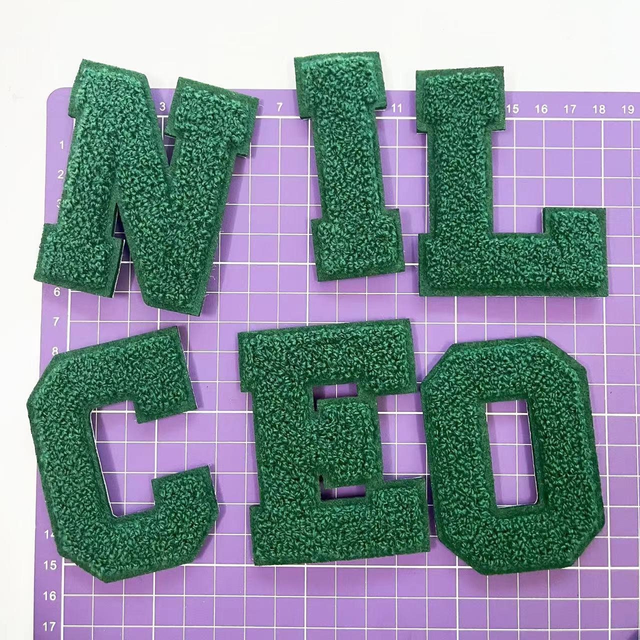 グリーンのシェニール刺繍文字を縫い付けたアップリケパッチ。衣類