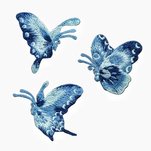 May include: Three blue embroidered butterfly patches. The butterflies have a light blue and dark blue colour gradient.
