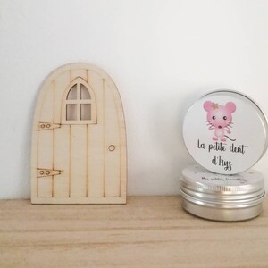 May include: A wooden fairy door with a small window and a silver tin with a pink mouse illustration and the text "La petite dent d'Ilys".