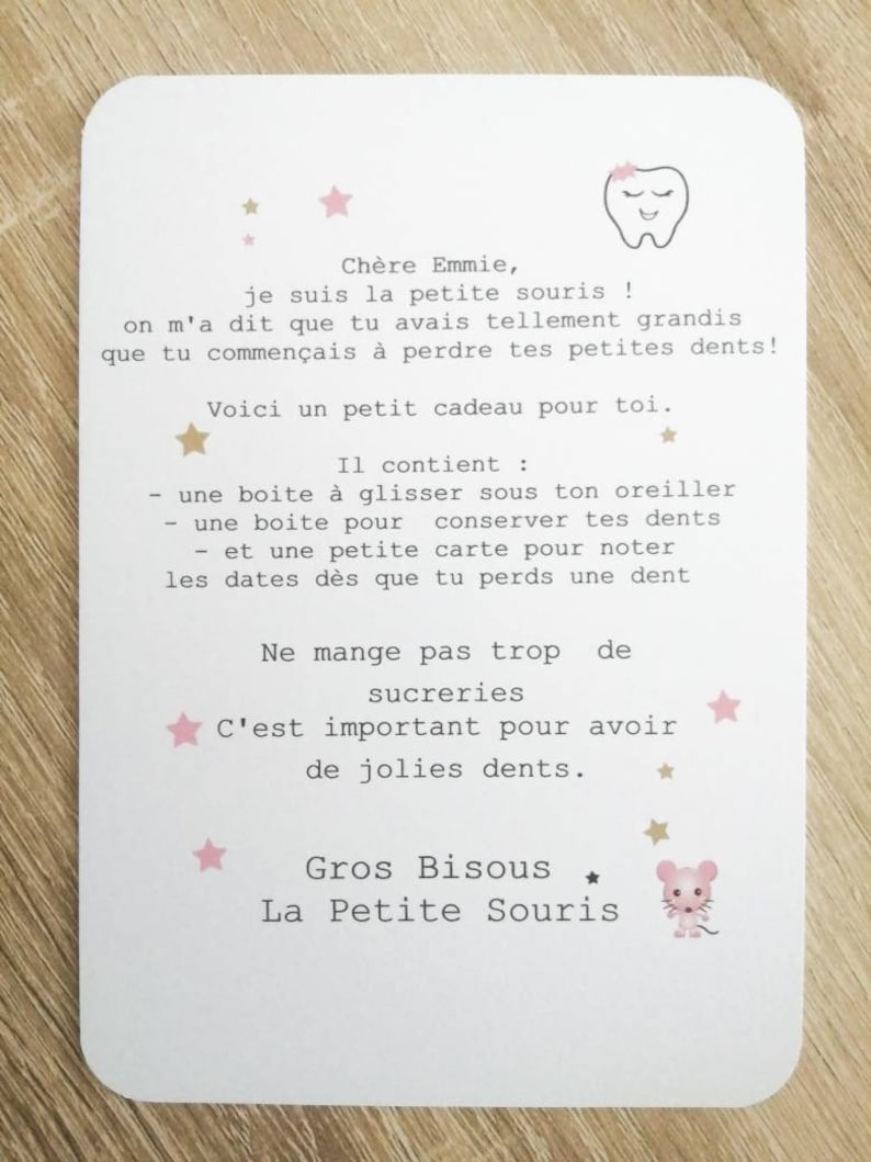 May include: A pink and white card with a tooth illustration and stars. The card has a message for a child who is losing their baby teeth. The message says "Ch&egrave;re Emmie, je suis la petite souris! On m'a dit que tu avais tellement grandis que tu commen&ccedil;ais &agrave; perdre tes petites dents! Voici un petit cadeau pour toi. Il contient: - une bo&icirc;te &agrave; glisser sous ton oreiller - une bo&icirc;te pour conserver tes dents - et une petite carte pour noter les dates d&egrave;s que tu perds une dent. Ne mange pas trop de sucreries C'est important pour avoir de jolies dents. Gros Bisous ★ La Petite Souris"