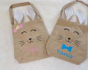 May include: Two burlap tote bags with bunny ears, one with pink flowers and the name "Lylah" and the other with a blue bow and the name "Yanis".