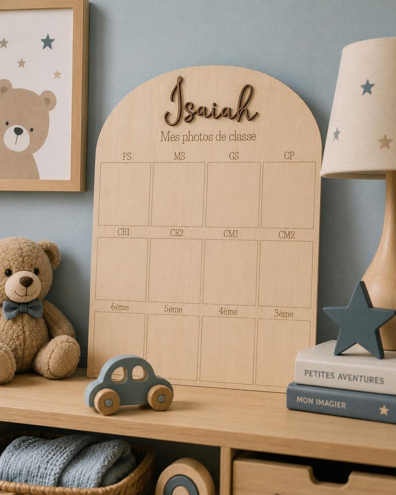 May include: Wooden photo display board with the name "Isaiah" and the text "Mes photos de classe". The board has spaces for school photos and is decorated with a teddy bear, a toy car, and a star-shaped lamp.