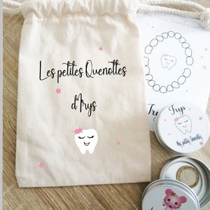 May include: A white cotton drawstring bag with the text "Les petites Quenottes d'Prys" and a pink tooth with a pink bow. There are three small silver tins with pink and white designs. One tin has the text "La petite dent d'lrys" and a pink mouse. Another tin has the text "Trys" and a pink tooth. The third tin has the text "Mes petites Quenottes" and a pink tooth.