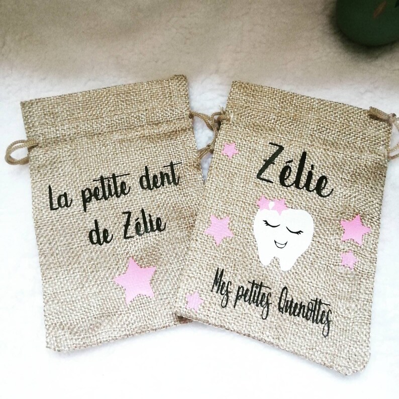 May include: Two small hessian bags with pink stars and a tooth graphic. One bag says "La petite dent de Z&eacute;lie" and the other says "Z&eacute;lie" and "Mes petites quenottes".