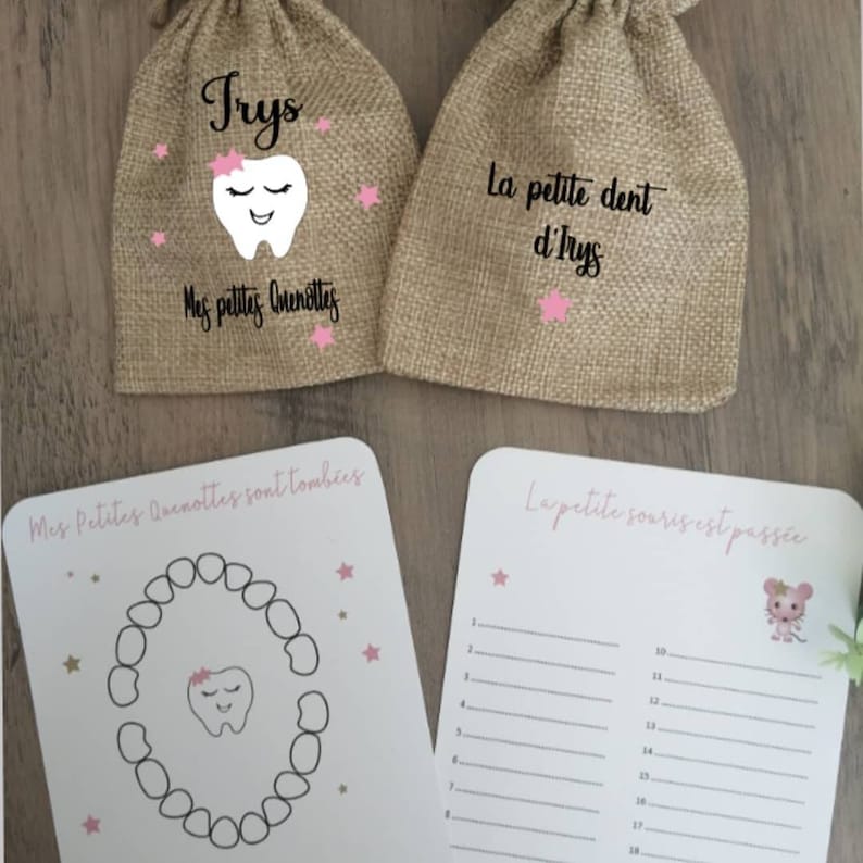 May include: Two burlap bags with pink stars and a tooth graphic. The text on the bags reads "Trys" and "La petite dent d'Irys". A white card with a tooth chart and pink stars. The text on the card reads "Mes Petites Quenottes sont tomb&eacute;es". A second white card with a pink mouse graphic and lines for writing. The text on the card reads "La petite souris est pass&eacute;e".
