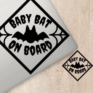 Könnte beinhalten: Ein schwarz-weißes Baby an Bord Schild mit einer Fledermaus-Silhouette und einem Spinnennetz-Design. Der Text lautet "Baby Bat On Board".