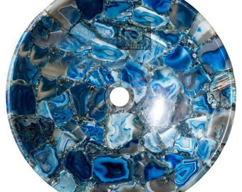 Pode incluir: Lavatório redondo de pedra de ágata azul e cinza com um orifício de drenagem central. A superfície é um mosaico de peças irregulares, mostrando uma gama de tons de azul, de claros a escuros, intercalados com cinza e branco. Um elemento decorativo natural.