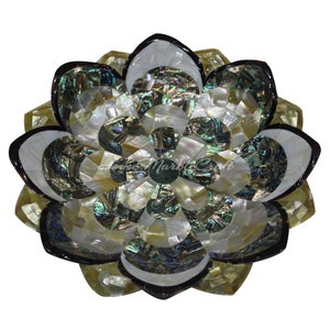 Op de afbeelding: Een decoratief lotusbloemontwerp in mozaïekstijl. De bloem is gemaakt van iriserende, veelkleurige stukken, met een donkere rand. Het midden van de bloem is donkergroen van kleur. Het algehele ontwerp is cirkelvormig en symmetrisch.