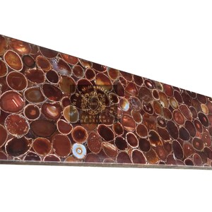 May include: A rectangular countertop made from polished agate slices in shades of brown, red, and cream. The agate pieces are arranged in a mosaic pattern. The countertop has a glossy finish and a natural appearance. The text "CARVING THE DREAMS" is visible.