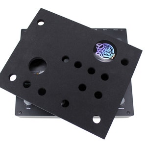 Può includere: Copertura in schiuma nera con ritagli per manopole e un adesivo che dice "Dub Spencer" su un dispositivo elettronico nero con manopole etichettate come "Drive", "Saturation" e "Onance".