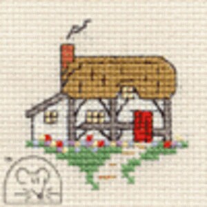 May include: A cross-stitch pattern featuring a small cottage with a thatched roof, a red door, and a chimney with smoke. The house is framed by green grass and colorful flowers. A small mouse icon is located in the bottom left corner of the fabric.
