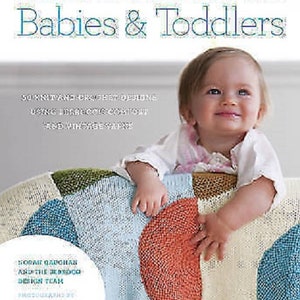 May include: A book cover with the title "Babies & Toddlers" and the text "Comfort Knitting & Crochet." A baby is sitting on a colorful knitted blanket. The blanket has patches of blue, orange, green, and cream colors. The book cover also includes text about the book's contents.