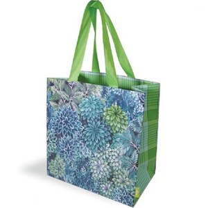 May include: A reusable shopping bag with a floral design. The bag features a pattern of blue, green, and white flowers and foliage. The handles are a bright green, and the bag has a plaid pattern on the sides.
