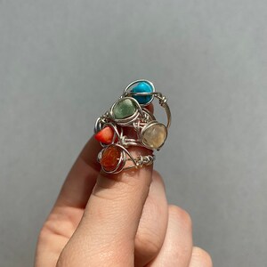 Peut inclure: Ensemble de quatre bagues en fil de fer avec des pierres pr&eacute;cieuses de diff&eacute;rentes couleurs. Les bagues pr&eacute;sentent une pierre turquoise, verte, blanche et orange.