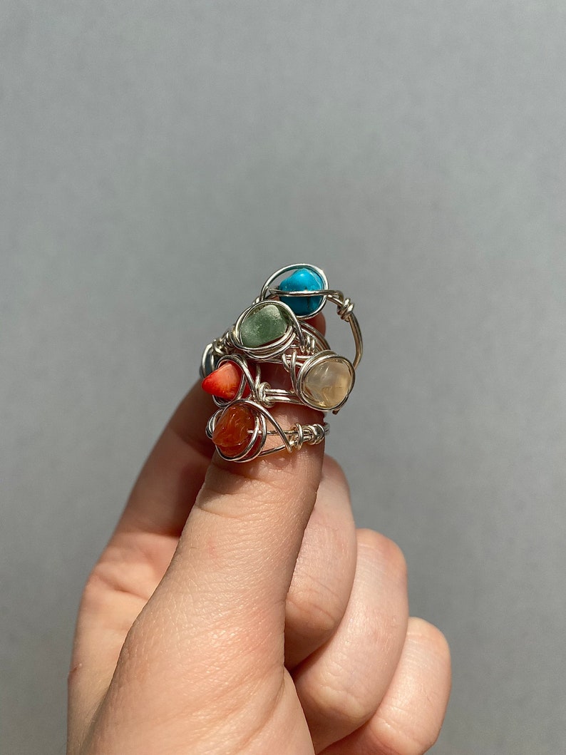 Peut inclure: Ensemble de quatre bagues en fil de fer avec des pierres pr&eacute;cieuses de diff&eacute;rentes couleurs. Les bagues pr&eacute;sentent une pierre turquoise, verte, blanche et orange.