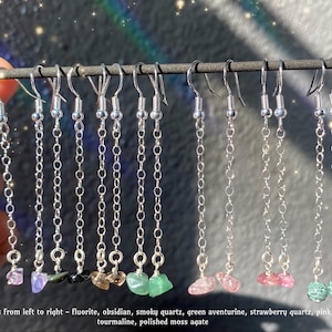 May include: Ten pairs of silver chain earrings with various semi-precious stones, including fluorite, obsidian, smoky quartz, green aventurine, strawberry quartz, pink tourmaline, and polished moss agate.