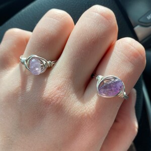 Peut inclure: Deux bagues en fil d'argent avec des pierres d'am&eacute;thyste. Les bagues sont sur les doigts d'une personne.
