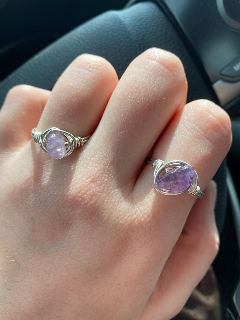 Peut inclure: Deux bagues en fil d'argent avec des pierres d'am&eacute;thyste. Les bagues sont sur les doigts d'une personne.