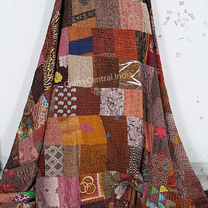 Könnte beinhalten: Eine Patchwork-Decke aus verschiedenen bunten Stoffen. Die Decke ist braun, orange, rosa, blau und grün. Sie besteht aus vielen verschiedenen Stoffquadraten, die zusammengenäht sind. Die Decke ist gefaltet und über eine weiße Wand gelegt. Der Text "Crafts Central India" ist in der Mitte der Decke sichtbar.