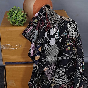 Può includere: Trapunta kantha nera con un motivo floreale e cuciture intricate. La trapunta è drappeggiata su una scatola di cartone e un vaso di terracotta.