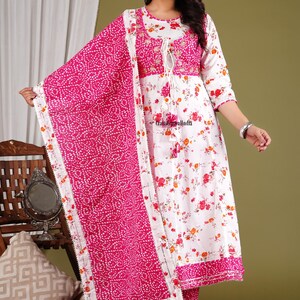 May include: A white and pink floral print kurta with a matching pink dupatta. The kurta has a round neckline and three-quarter sleeves. The dupatta has a white border with a pink and white polka dot pattern. The kurta and dupatta are made of cotton.