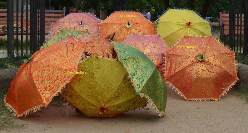 May include: A collection of colorful umbrellas with gold accents and fringe trim. The umbrellas are made of fabric and have a traditional design.