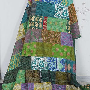 Könnte beinhalten: Ein Patchwork-Quilt aus verschiedenen grünen, blauen und violetten Stoffen. Der Quilt zeigt florale, Paisley- und geometrische Muster. Der Text "Crafts Central India" ist auf dem Quilt zu sehen.