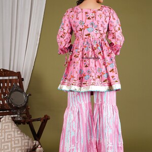 Op de afbeelding: Een roze en blauwe, met bloemen bedrukte kurta met een uitlopende vorm en een bijpassende palazzo broek. De kurta heeft een ronde hals en driekwart mouwen. De palazzo broek heeft een wijde pijp en een uitlopende zoom.
