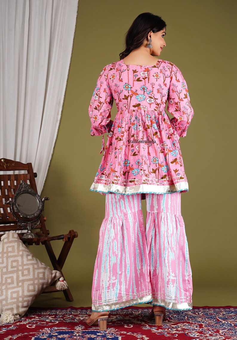 Op de afbeelding: Een roze en blauwe, met bloemen bedrukte kurta met een uitlopende vorm en een bijpassende palazzo broek. De kurta heeft een ronde hals en driekwart mouwen. De palazzo broek heeft een wijde pijp en een uitlopende zoom.