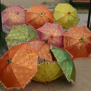 May include: A collection of colorful, patterned umbrellas with fringe trim. The umbrellas are made of fabric and have a variety of colors, including red, orange, yellow, green, and pink.