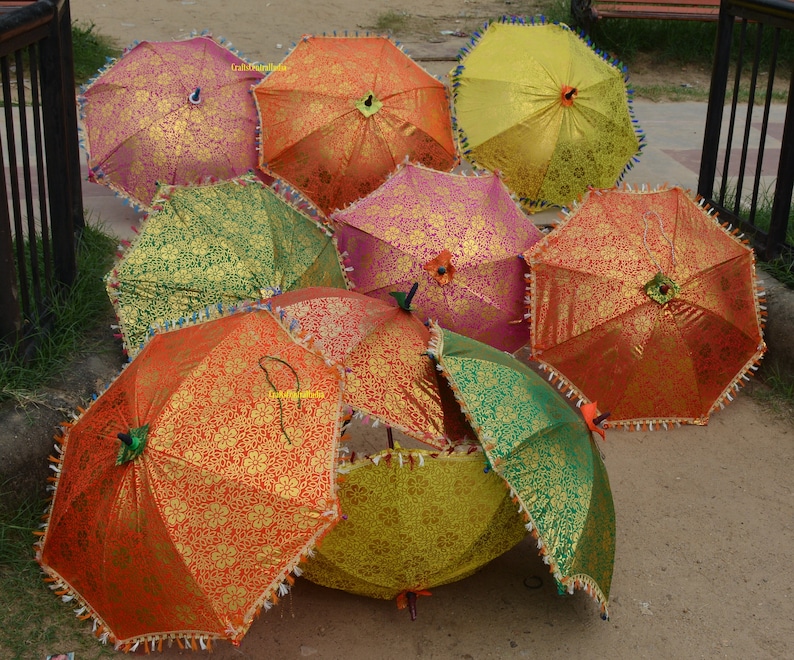 May include: A collection of colorful, patterned umbrellas with fringe trim. The umbrellas are made of fabric and have a variety of colors, including red, orange, yellow, green, and pink.