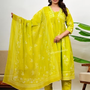 Könnte beinhalten: Ein limettengrünes dreiteiliges Set bestehend aus einem plissierten Kurta mit Spiegelverzierungen am V-Ausschnitt, einer passenden Hose mit geradem Bein und einem leichten Dupatta, alles mit einem dezenten weißen Blumenmuster.