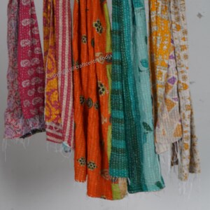 Puede incluir: Seis colchas kantha de colores colgando de una pared blanca. Las colchas est&aacute;n hechas de saris reciclados y presentan una variedad de patrones y colores, incluyendo rosa, naranja, amarillo, verde y azul. Copyright @craftcentralindia