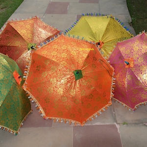 May include: Five colorful umbrellas with gold accents and fringe trim. The umbrellas are made of fabric and have a traditional design.