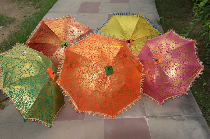 May include: Five colorful umbrellas with gold accents and fringe trim. The umbrellas are made of fabric and have a traditional design.