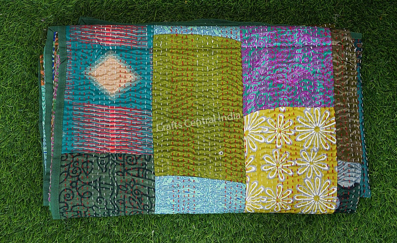 May include: A colorful patchwork quilt with a variety of floral and geometric patterns. The quilt is made of different fabrics sewn together and has a hand-stitched look. The quilt is green, blue, yellow, red, and purple.