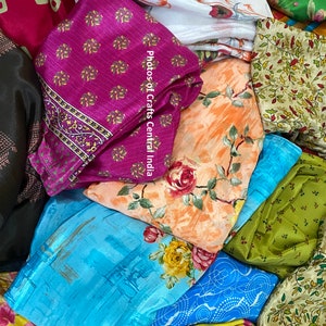 Könnte beinhalten: Ein Stapel bunter Stoffreste mit floralen und geometrischen Mustern. Die Stoffe sind aus Seide und Baumwolle. Der Text "Photos of Crafts Central India" ist auf dem Stoff sichtbar.