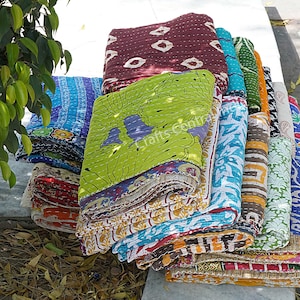 May include: A stack of colorful kantha quilts with various patterns and designs. The quilts are made of recycled saris and are a popular choice for home decor and gifts.