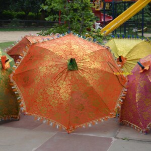 May include: Four decorative umbrellas with gold and colored fabric. The umbrellas are closed and have tassels around the edges.