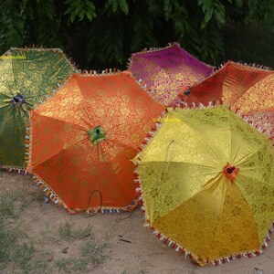 May include: Five colorful umbrellas with intricate patterns and fringed edges. The umbrellas are in shades of green, orange, yellow, pink, and red.