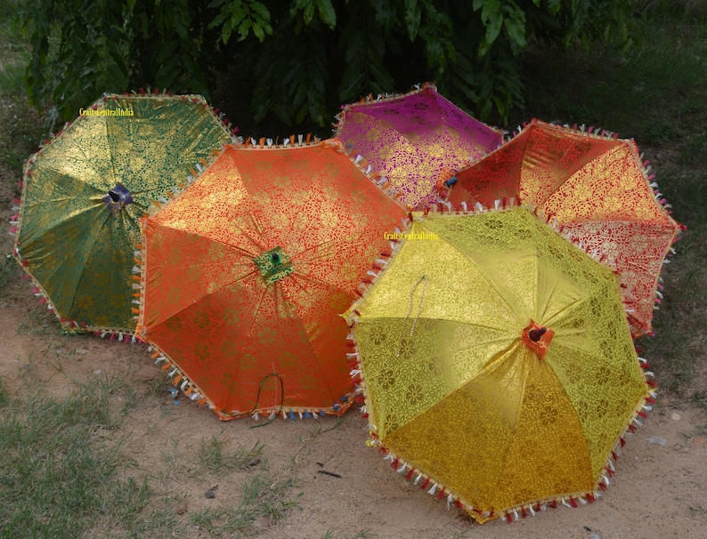May include: Five colorful umbrellas with intricate patterns and fringed edges. The umbrellas are in shades of green, orange, yellow, pink, and red.
