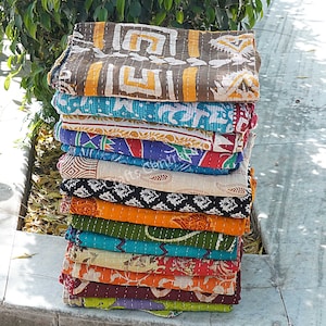May include: A stack of 14 colorful kantha quilts, each with a different pattern. The quilts are made of cotton and are hand-stitched. They are perfect for adding a touch of bohemian style to your home.