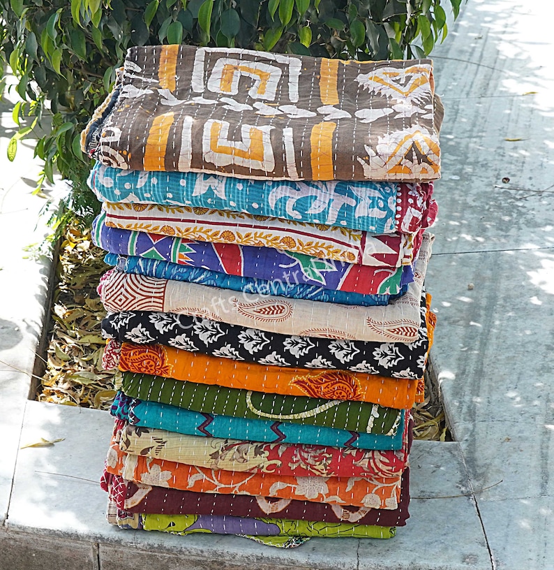 May include: A stack of 14 colorful kantha quilts, each with a different pattern. The quilts are made of cotton and are hand-stitched. They are perfect for adding a touch of bohemian style to your home.
