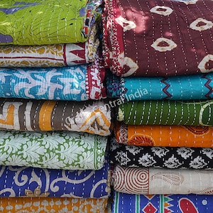 May include: A stack of colorful kantha quilts with various patterns and designs. The quilts are made of recycled saris and are hand-stitched. The quilts are a popular choice for home decor and are known for their unique and beautiful designs.