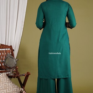 May include: A teal green kurta and palazzo set with gold embroidery. The set is made of a soft, flowy fabric and is perfect for a casual or semi-formal occasion. The model is wearing the set with a pair of gold earrings and a simple necklace.