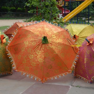 May include: Four decorative umbrellas with gold and colored fabric. The umbrellas are closed and have tassels around the edges.