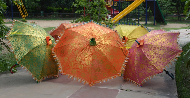 May include: Four decorative umbrellas with gold and colored fabric. The umbrellas are closed and have tassels around the edges.