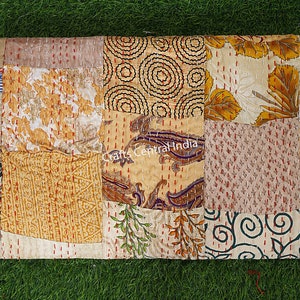 May include: A patchwork quilt made from various fabrics in shades of beige, brown, and gold. The quilt is made up of squares and rectangles of different sizes and patterns, including floral, paisley, and geometric designs. The quilt is hand-stitched and has a rustic, vintage look.