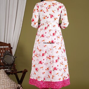 May include: A white floral print dress with a pink trim and matching pink pants. The dress has a V-neck and 3/4 sleeves.